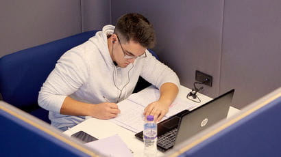 Student with a laptop working in a study booth.