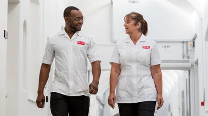 Two School of Health and Wellbeing staff walking through a building on Glenside Campus.