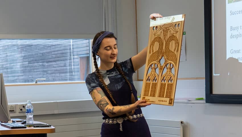 Student employed by New Wave, holding up an example of their work during a talk at the Professional Project Week.