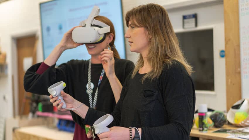 Student and mentor using VR headset to create 3D virtual art.