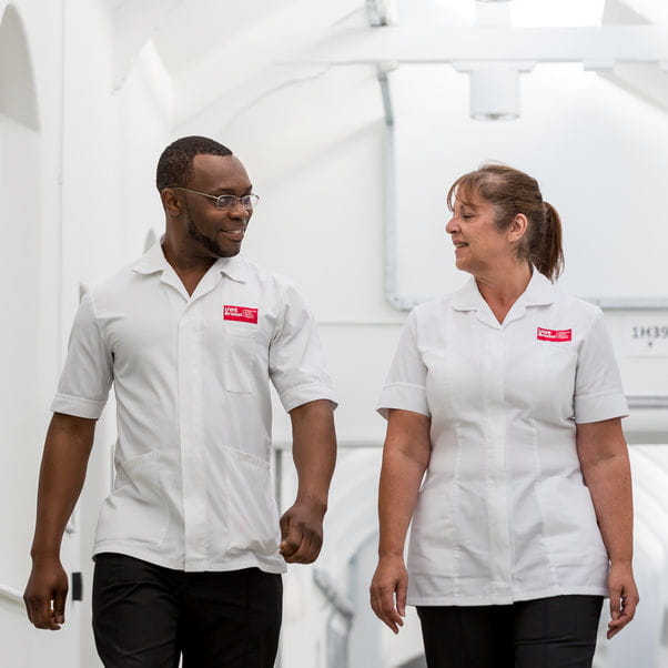 Two School of Health and Wellbeing staff walking through a building on Glenside Campus.