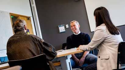 Three people sat around a table in discussion