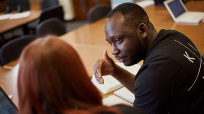 Two people talking in the library.