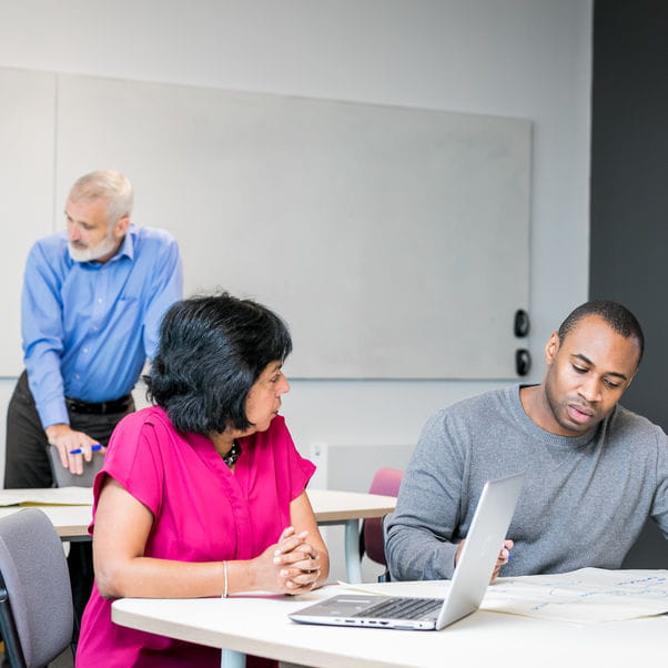 Three members of staff having conversations in an office.