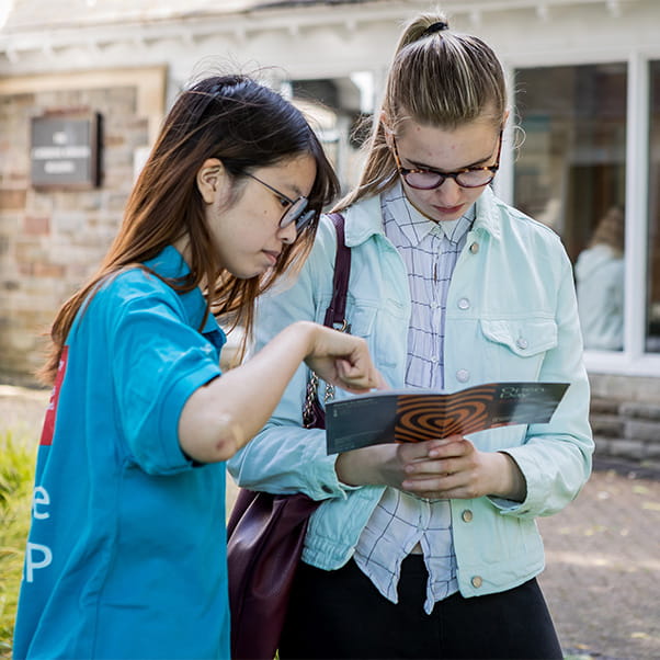 A UWE Bristol student ambassador helps show a visitor information in the open day guidebook.