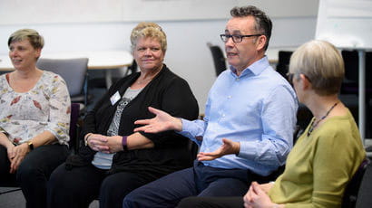 Group of people sat in a room talking.