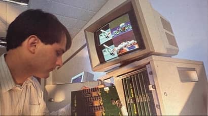 Boy sitting at desk looking at old style computer.