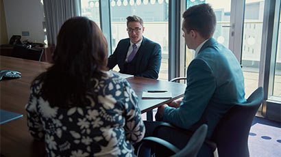 Three people sat chatting around a boardroom table