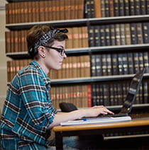 A student sat working at a laptop in a library setting