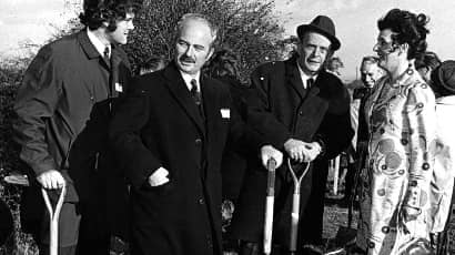Black and white photo of Dr Bolland standing with group of people.