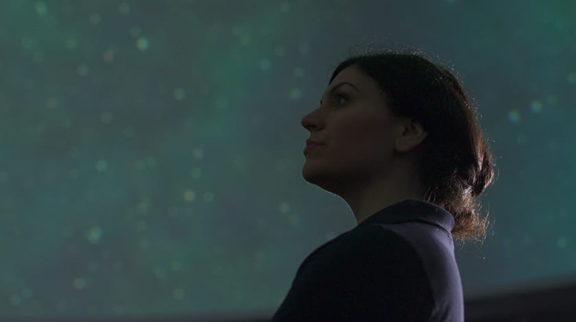 UWE Bristol alumnus Nicol Caplin with an image of the solar system in the background.