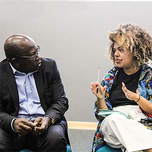 Two smartly dressed people talking in a room.