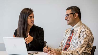 Two people in discussing next to a laptop