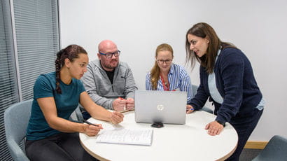 Four people working around a laptop