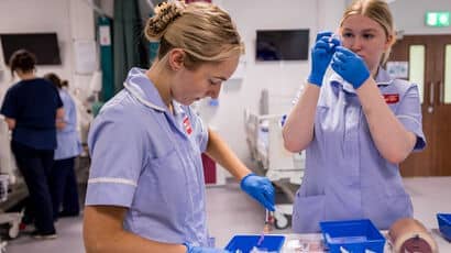 Two student nurses preparing syringes.