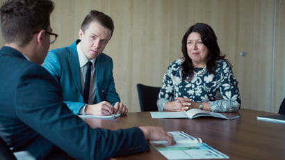 Two placement students in conversation with employer sitting around a table.