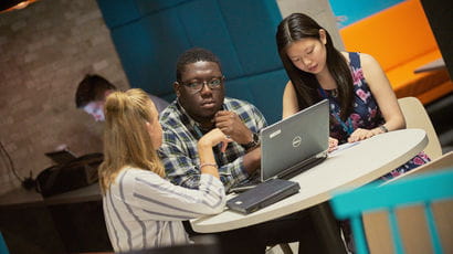 Three Intel placement students sat around a table with a laptop