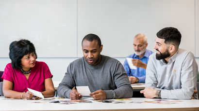 Group of people working around a computer.