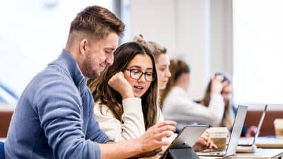 Two people working at a laptop.