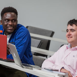 Two people studying in a lecture theatre.