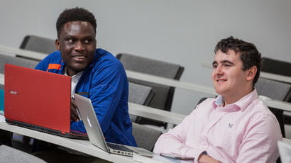 Two people sat listening in a lecture theatre.