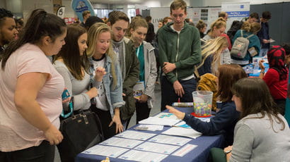 Group of people standing around table at a volunteering fair at the Frenchay campus.