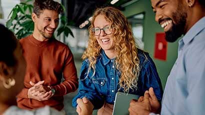 Group of people smiling, whilst the women is leaning in to shake another women's hand.