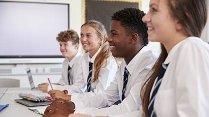 A teacher showing two students something on a laptop