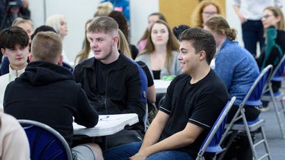 Group of young people sat at tables.