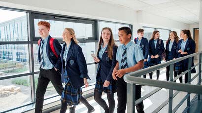 Group of secondary school children walking along a corridor.