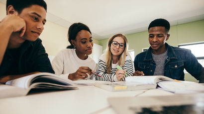 Four students in a classroom working from textbooks