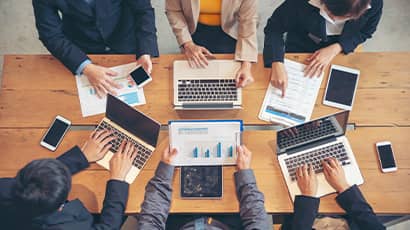 Top down view of table with people collaborating on a project together.