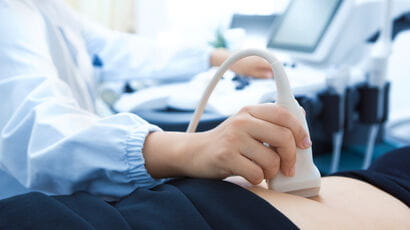 Sonographer using an ultrasound machine to assess a patients tummy.