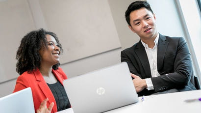 Two people having a conversation while using a laptop.