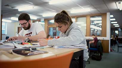 A male and female student studying together in the Library at Frenchay Campus.