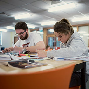Students in Frenchay library, studying at desks.