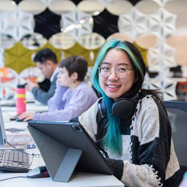 Girl smiling in a library with headset around her neck.