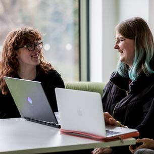 Smiling students sat with laptops