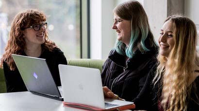 Smiling students sat with laptops