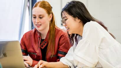 Two female students working together with a laptop.