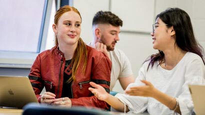 Couple of students talking at desk