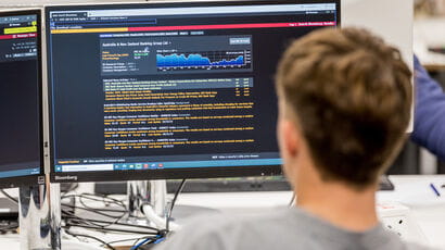 View of a Bloomberg financial terminal over the shoulder of a student.