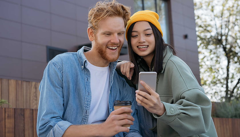 Two young adults looking at a phone and smiling.