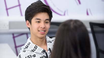 Student chatting to another student that has their back to the camera