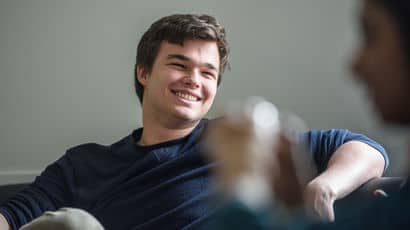 A student sat on a sofa and laughing with a friend
