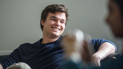 A student sat on a sofa and laughing with a friend