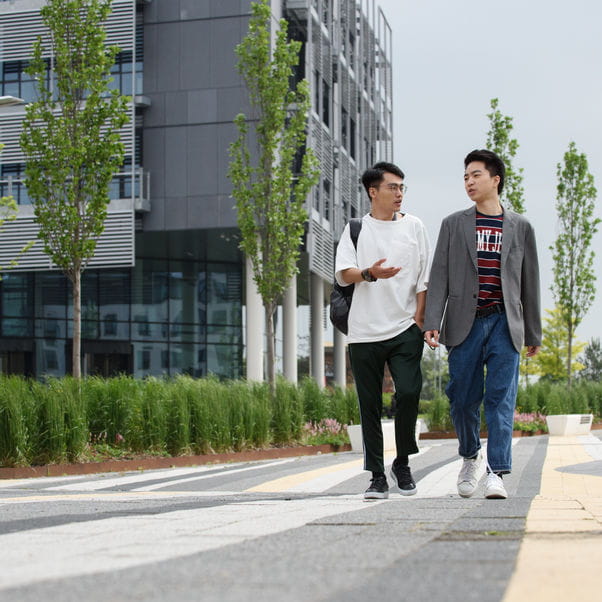 Two students walking past a University building