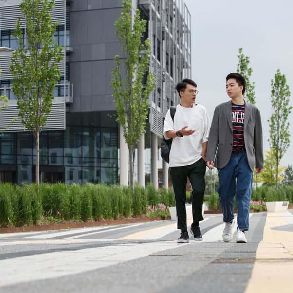 Two students walking past a University building