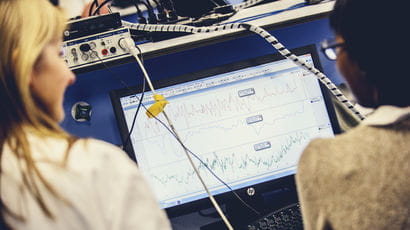 Two people using a computer hooked up to to technical equipment.