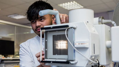 Radiotherapy student holding specialist equipment.
